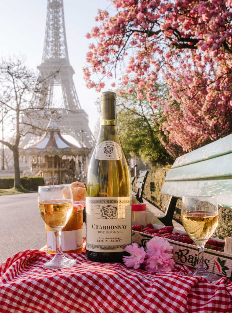 Bottle of Chardonnay on table in front of Eiffel Tower in Paris, France with two wine glasses