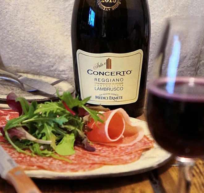 Bottle of Medici Ermete Concerto Lambrusco dry red wine from Emilia-Romagna next to Italian cured meats