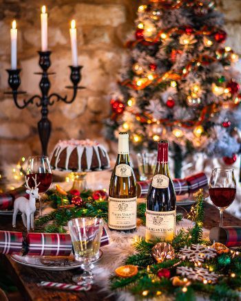 Louis Jadot wine at Christmas table with candles, tree, lights