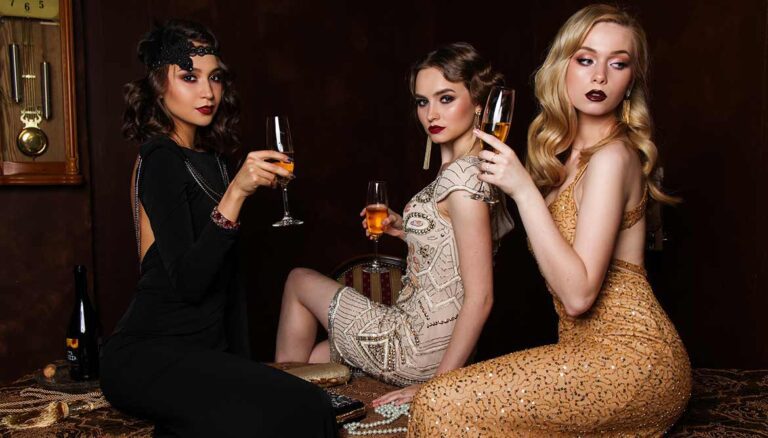 Three young women sitting and drinking Champagne from flutes and looking contemplative